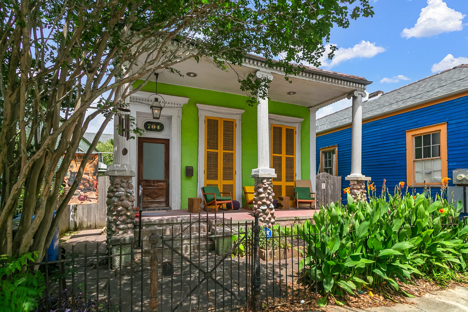 Historic New Orleans Creole cottage with a columned front porch and wrought-iron fence